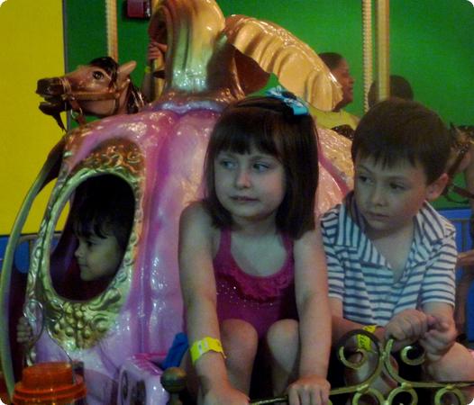 Everest and Karissa ride on a carousel in San Juan's Museo Histórico de la Biblia