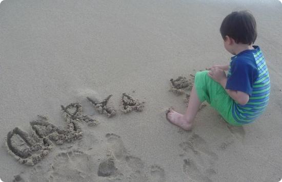 Everest writes his name and Darya's on Waikiki Beach