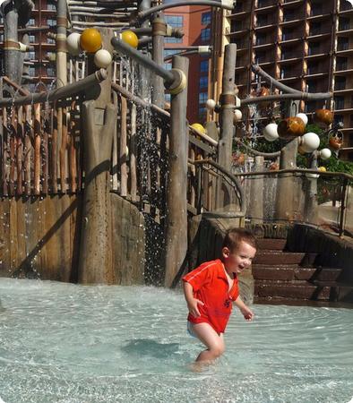 Eilan runs through the shallow water under the Menehune Bridge at Aulani Resort