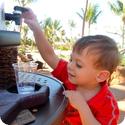 Eilan helps himself to a cup of water at a poolside water station at Aulani Resort